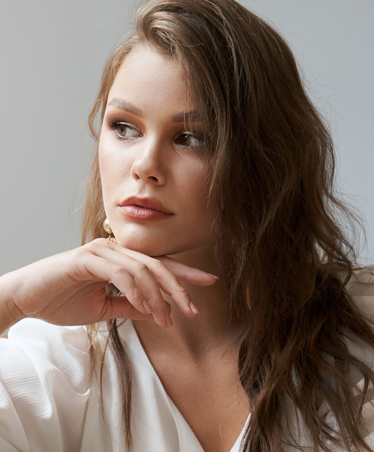 Woman in thoughtful pose with hand on chin.