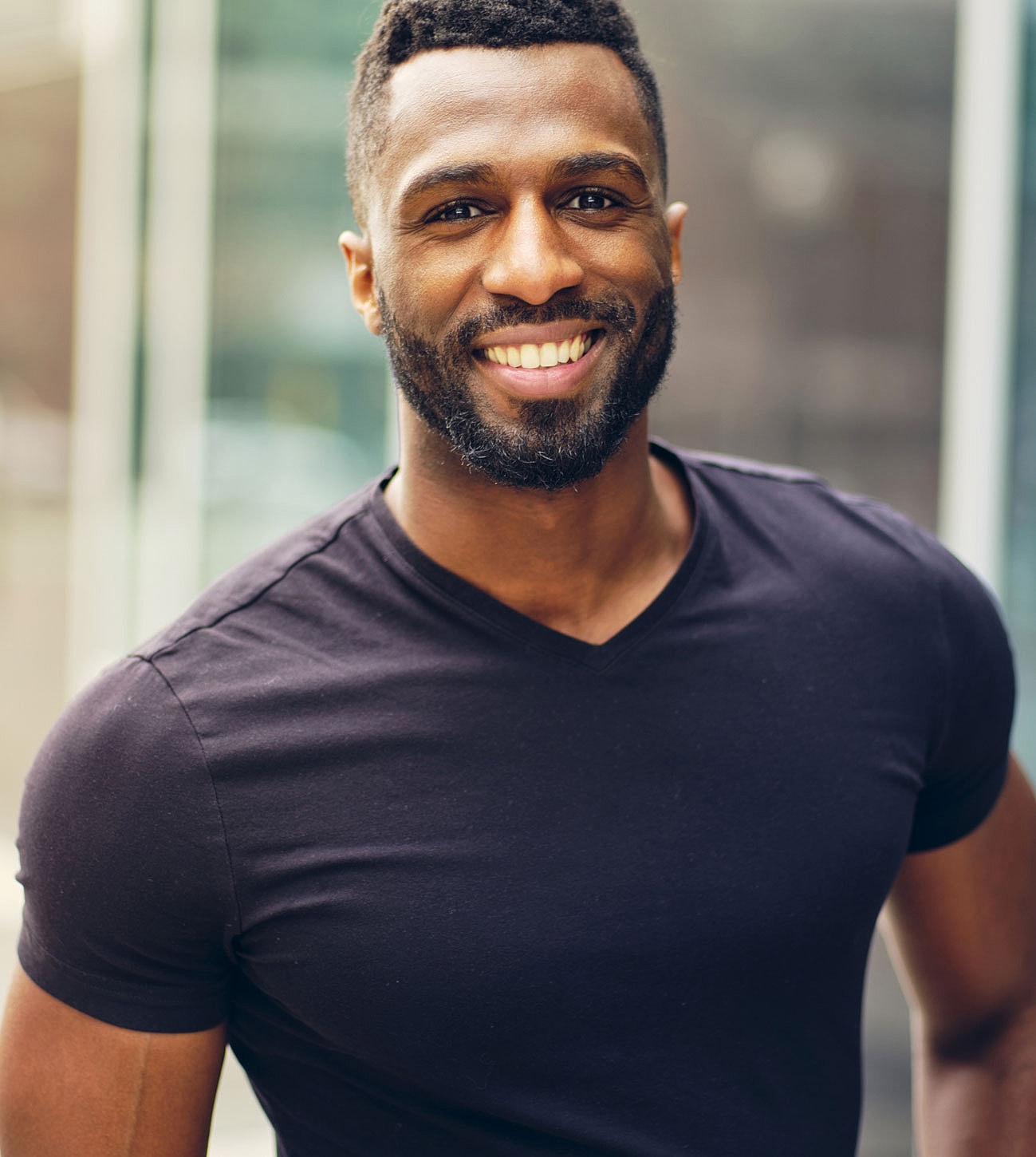 Smiling man in black shirt outdoors.