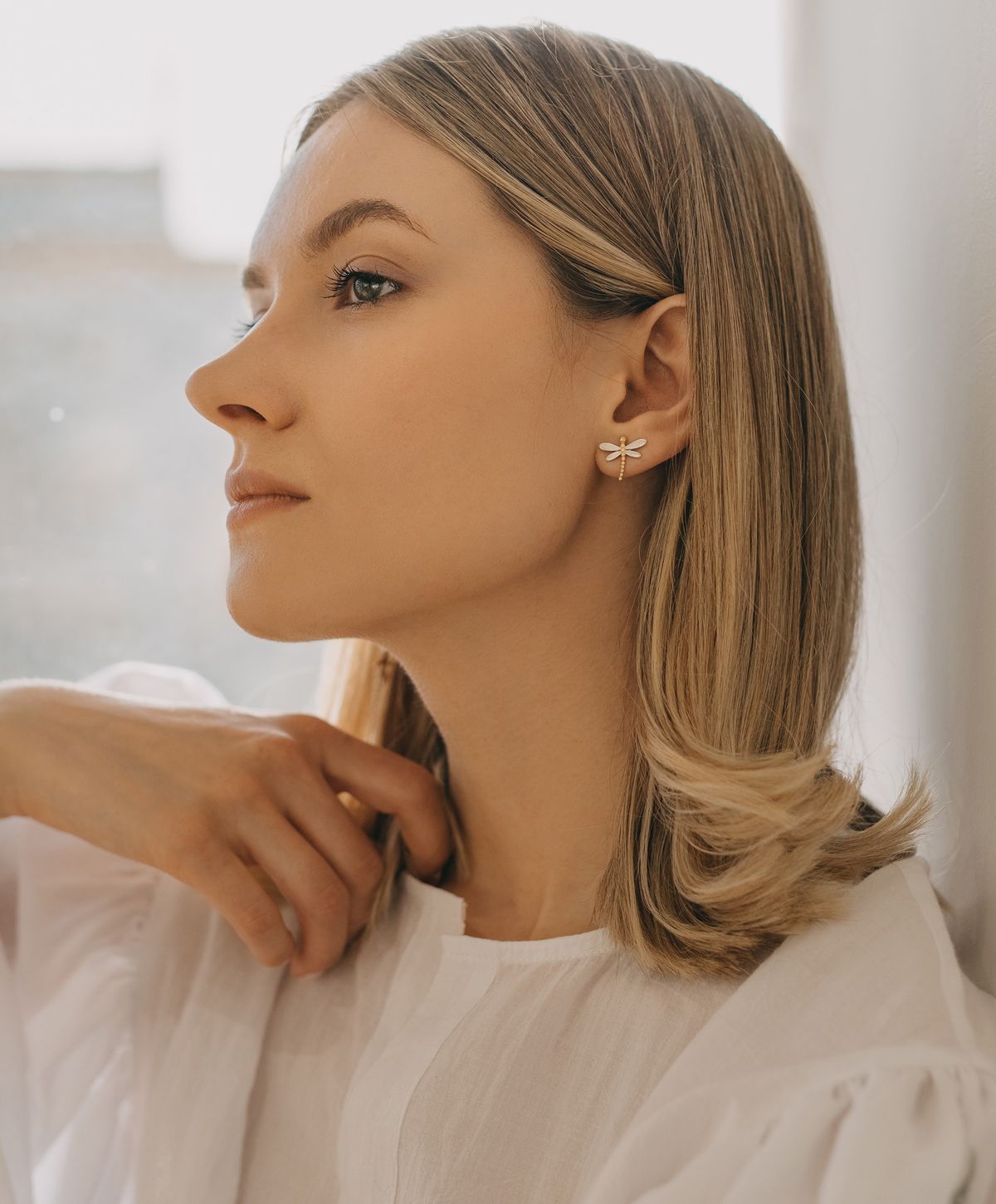 Model showcasing dragonfly earrings in natural light.